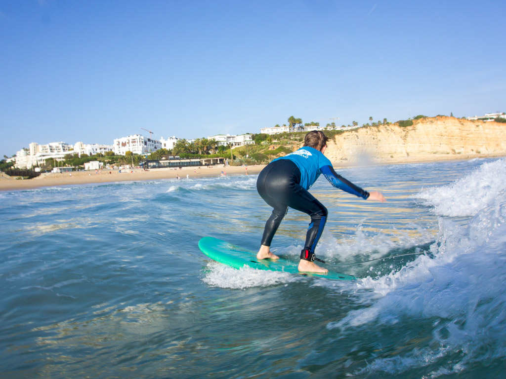 Surfcamp für Familien. Kind surft eine Welle in Porto de mos in der Algarve 
